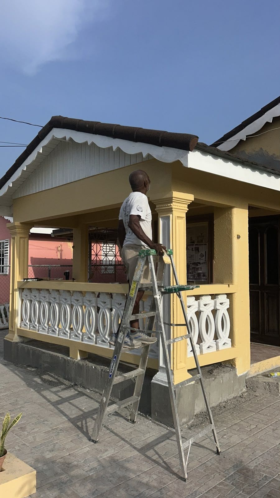 Painter finishing porch railing on ladder