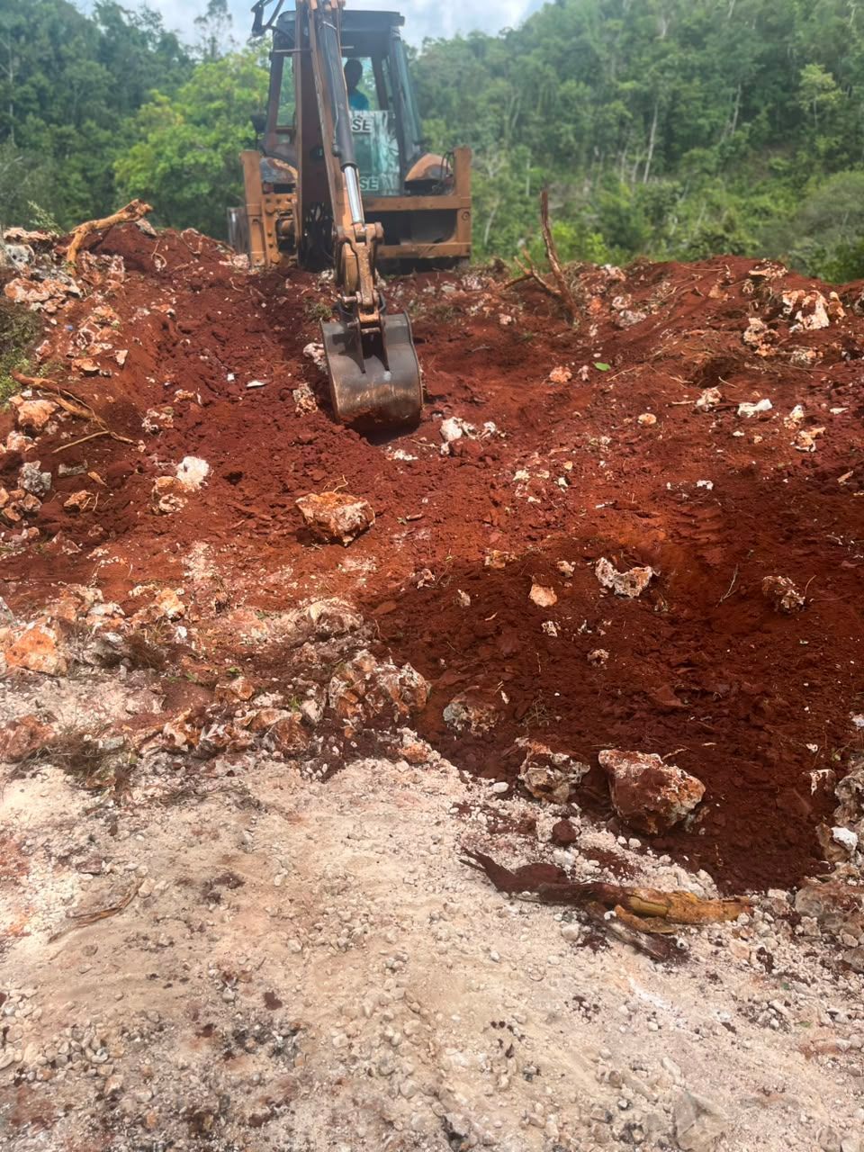 Excavator digging red earth foundation trench