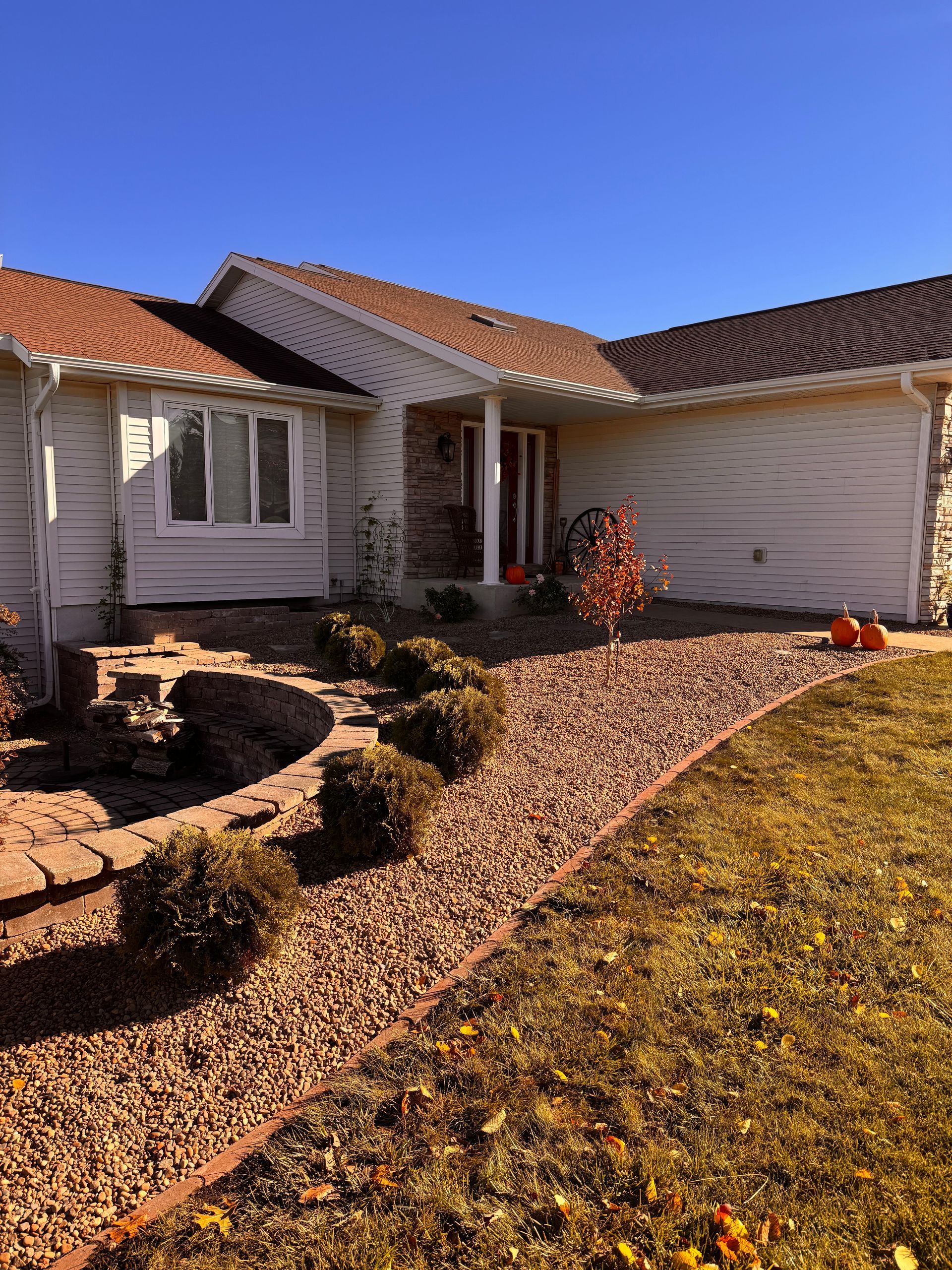 A beige house with a stone pathway, landscaping, and a blue sky.