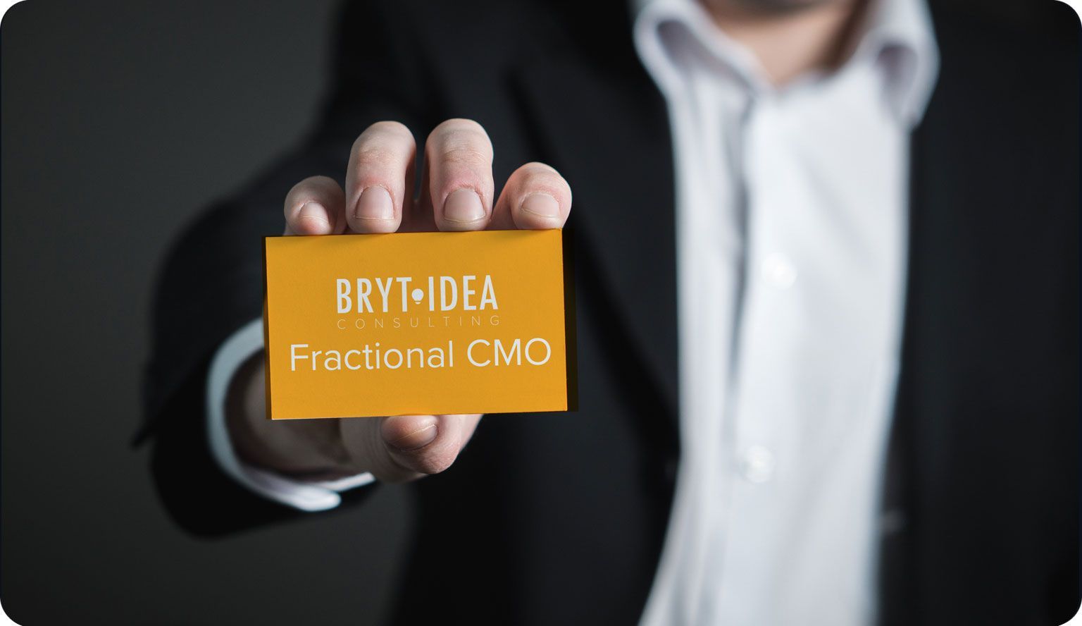 a man in a suit is holding a business card that says bryt idea consulting fractional cmo a man in a suit is holding a business card that says bryt idea consulting fractional cmo