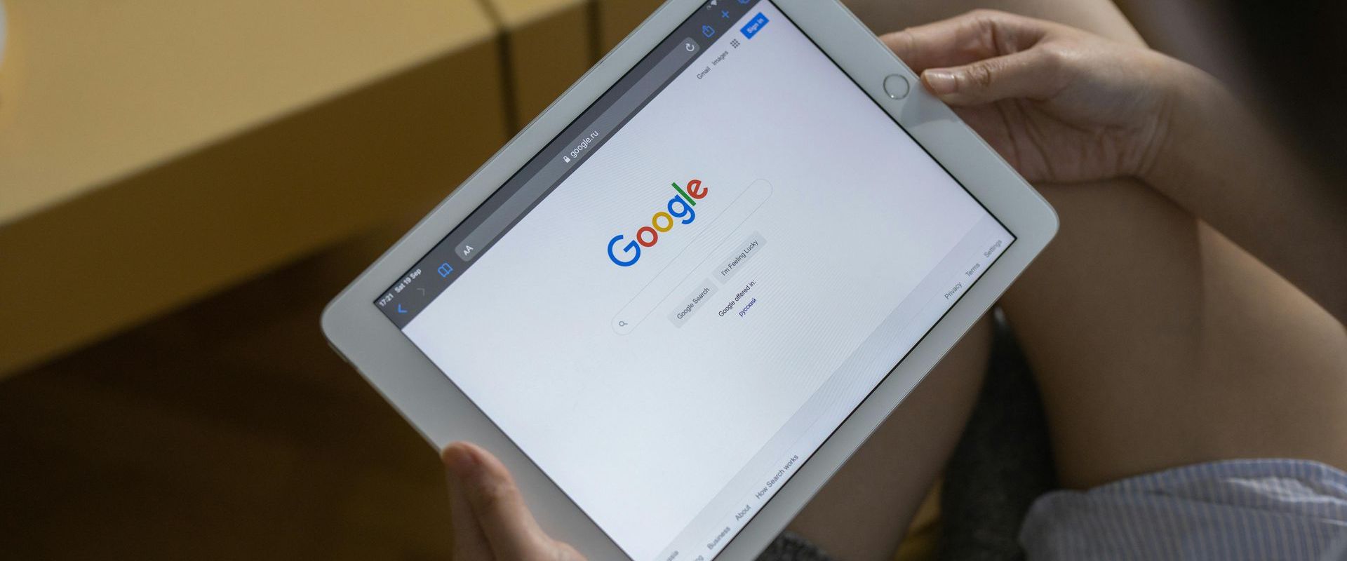 A person is holding a tablet with a google search page on it.