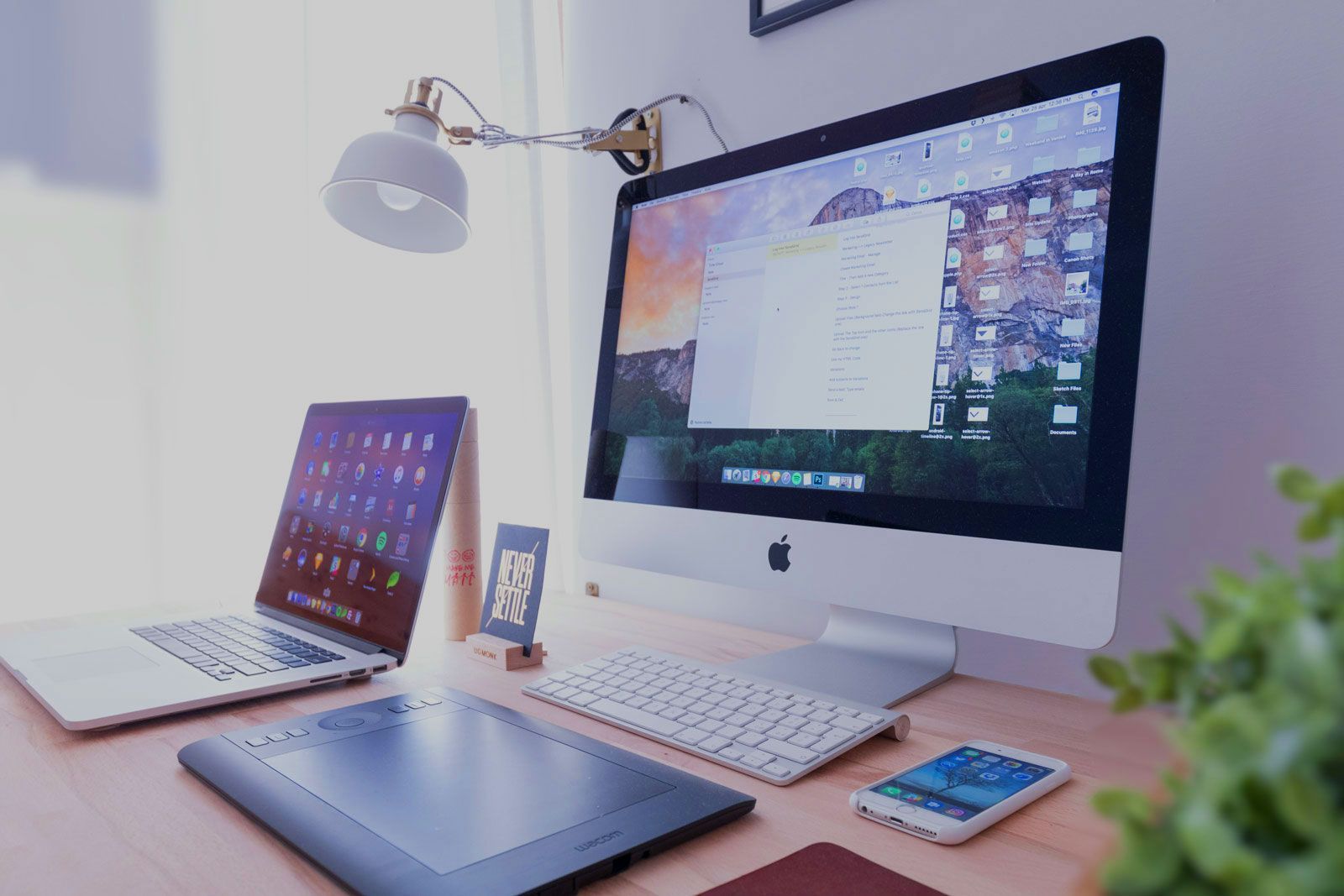 A computer monitor is sitting on a desk next to a laptop and a phone.