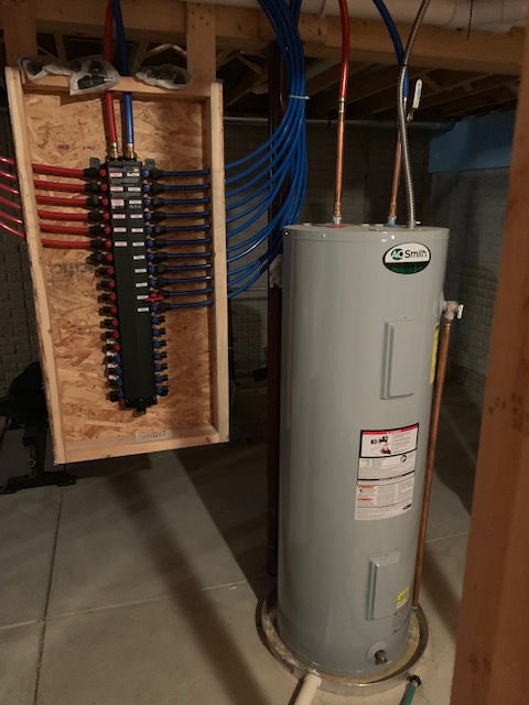 A basement plumbing setup featuring a vertical A.O. Smith water heater connected to a blue and red PEX manifold system.