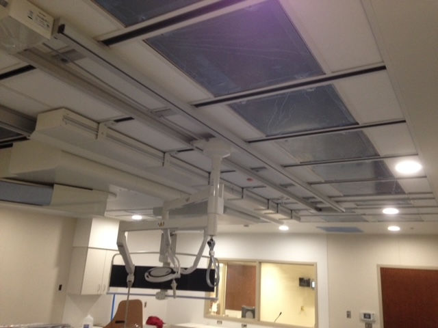 A ceiling-mounted medical equipment boom in a hospital room, featuring a track system and clinical lighting.