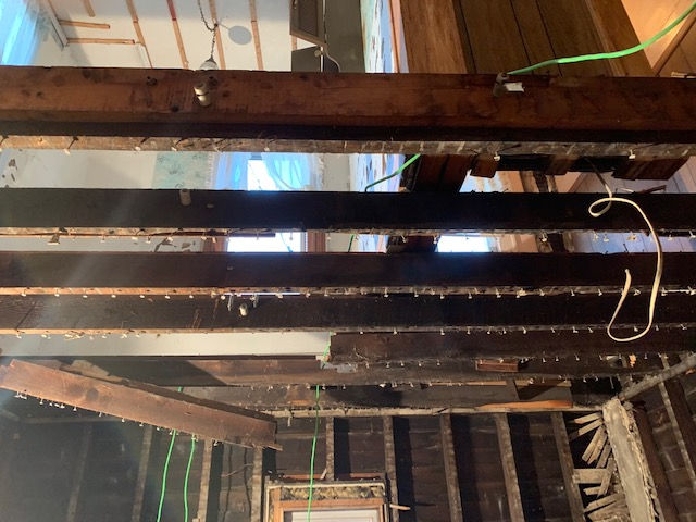 Interior view of exposed wooden ceiling joists and wall studs during a home renovation.