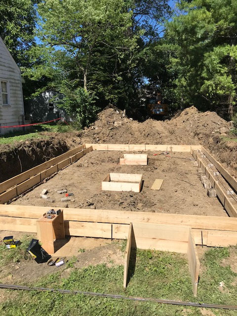 Wooden forms set into a dirt excavation area for a residential foundation construction project.
