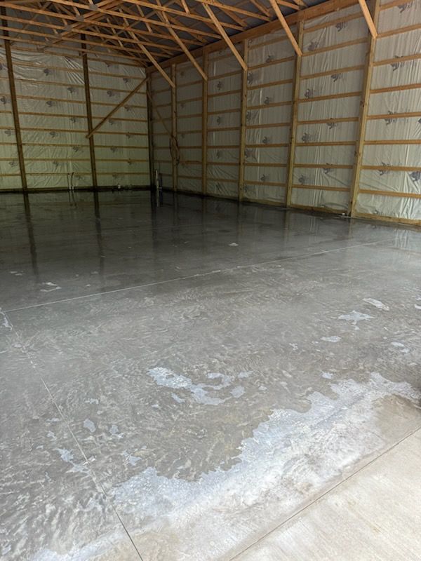 Empty unfinished garage with a concrete floor and exposed wooden roof framing