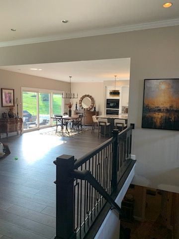 A view from a stairwell overlooking a bright, open-plan dining and kitchen area with large glass doors to a lawn.