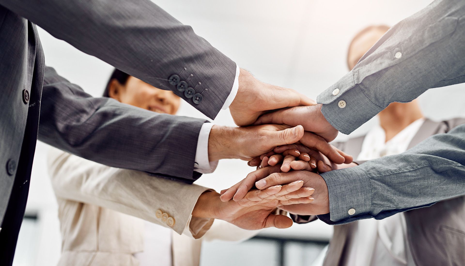 Hands stacked together in a team huddle, symbolizing unity and collaboration.