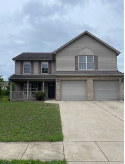 A large house with two garage doors and a concrete driveway