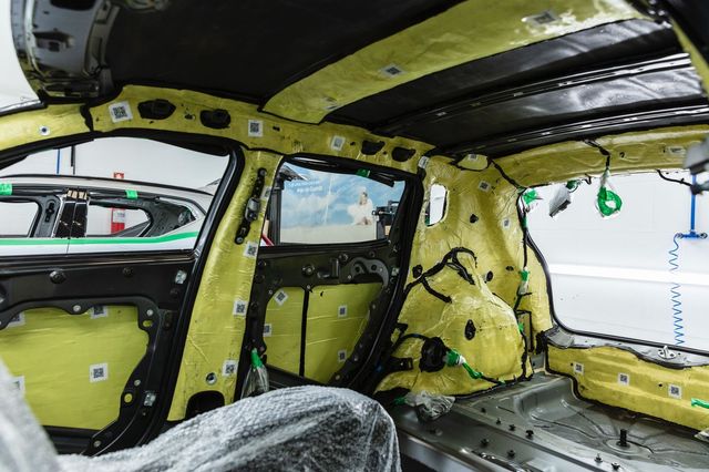 Um homem está trabalhando no interior de um carro em uma fábrica.