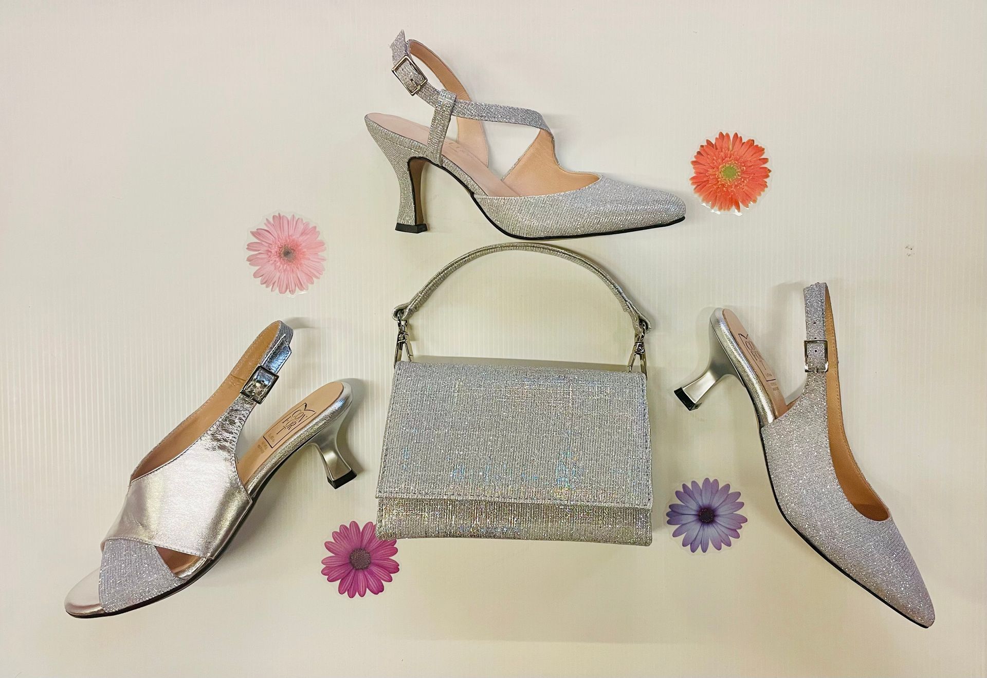 Scarpe argentate scintillanti e borsa coordinata decorata con fiori colorati.