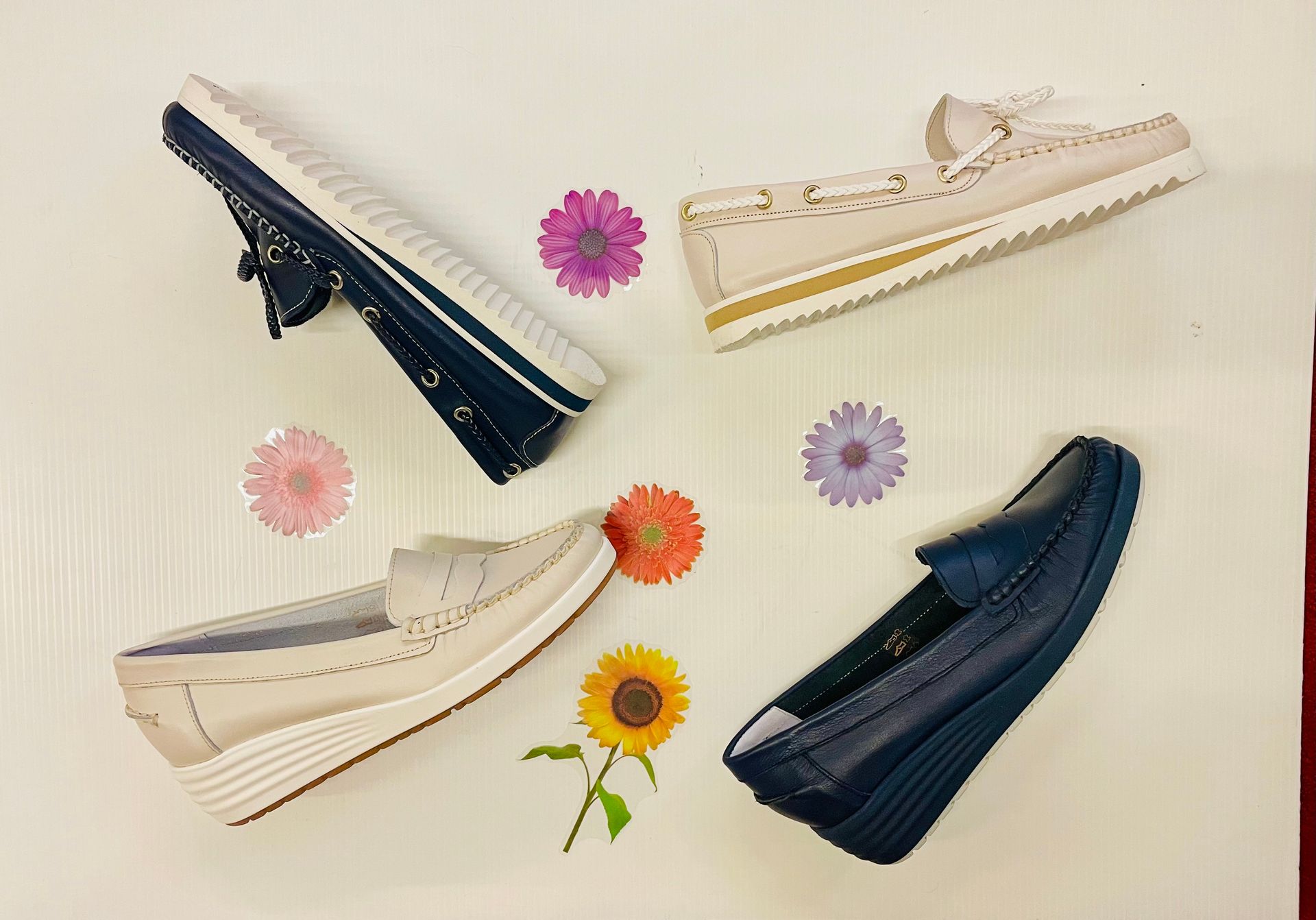 Quattro paia di mocassini da donna nei toni del blu e del beige, decorati con motivi floreali su una superficie bianca.