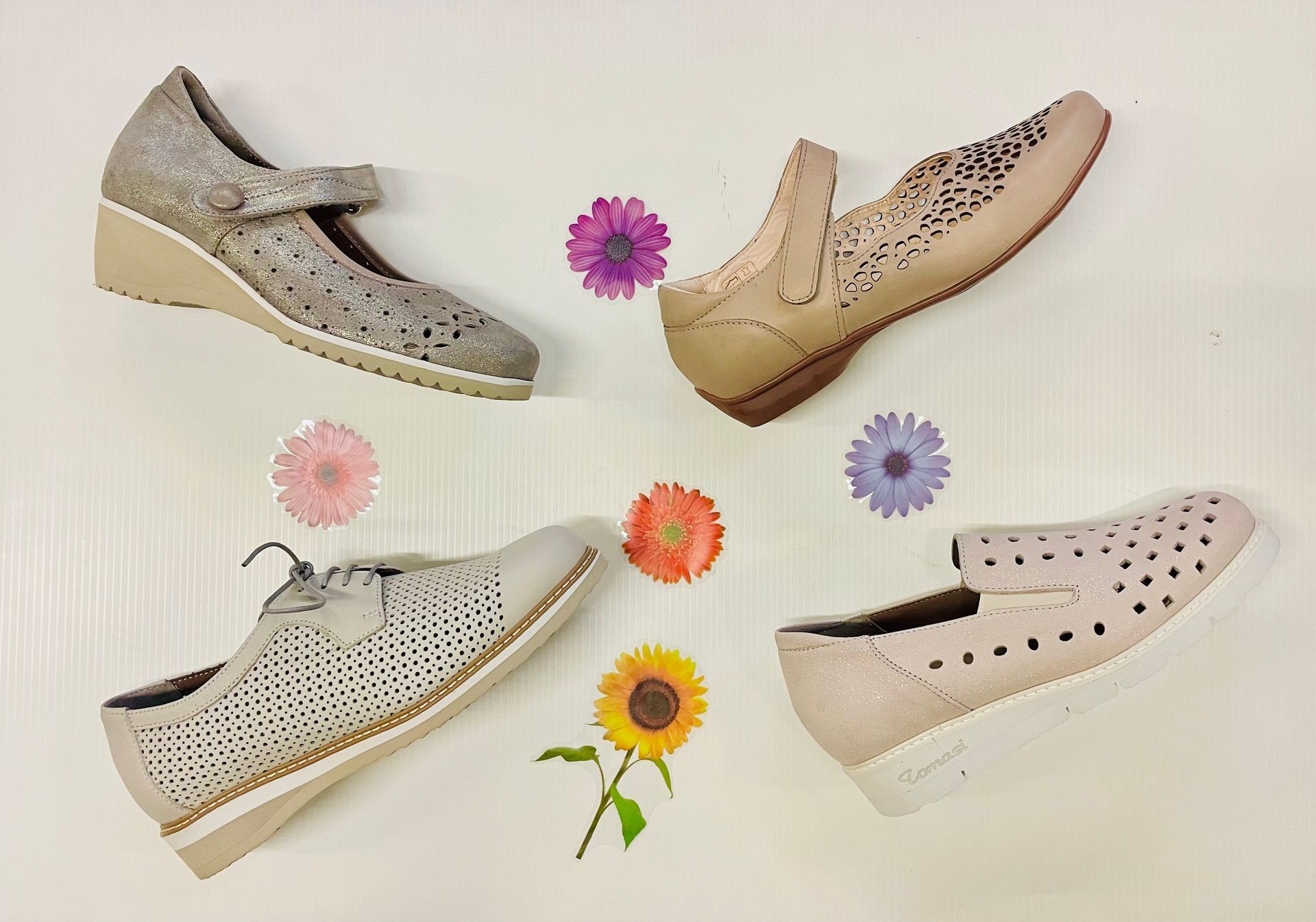 Quattro paia di scarpe da donna in stili diversi e tonalità beige, con decorazioni floreali su sfondo bianco.