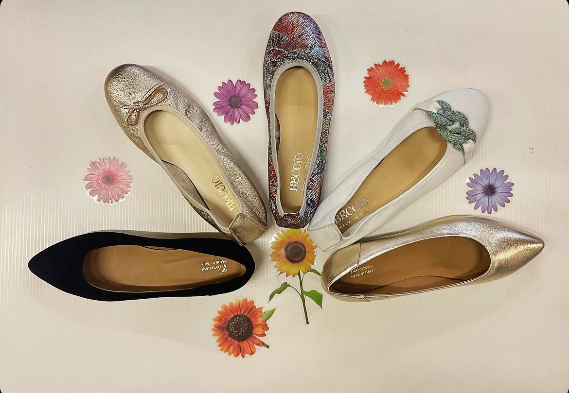 Cinque ballerine colorate con motivi floreali disposti su una superficie bianca.