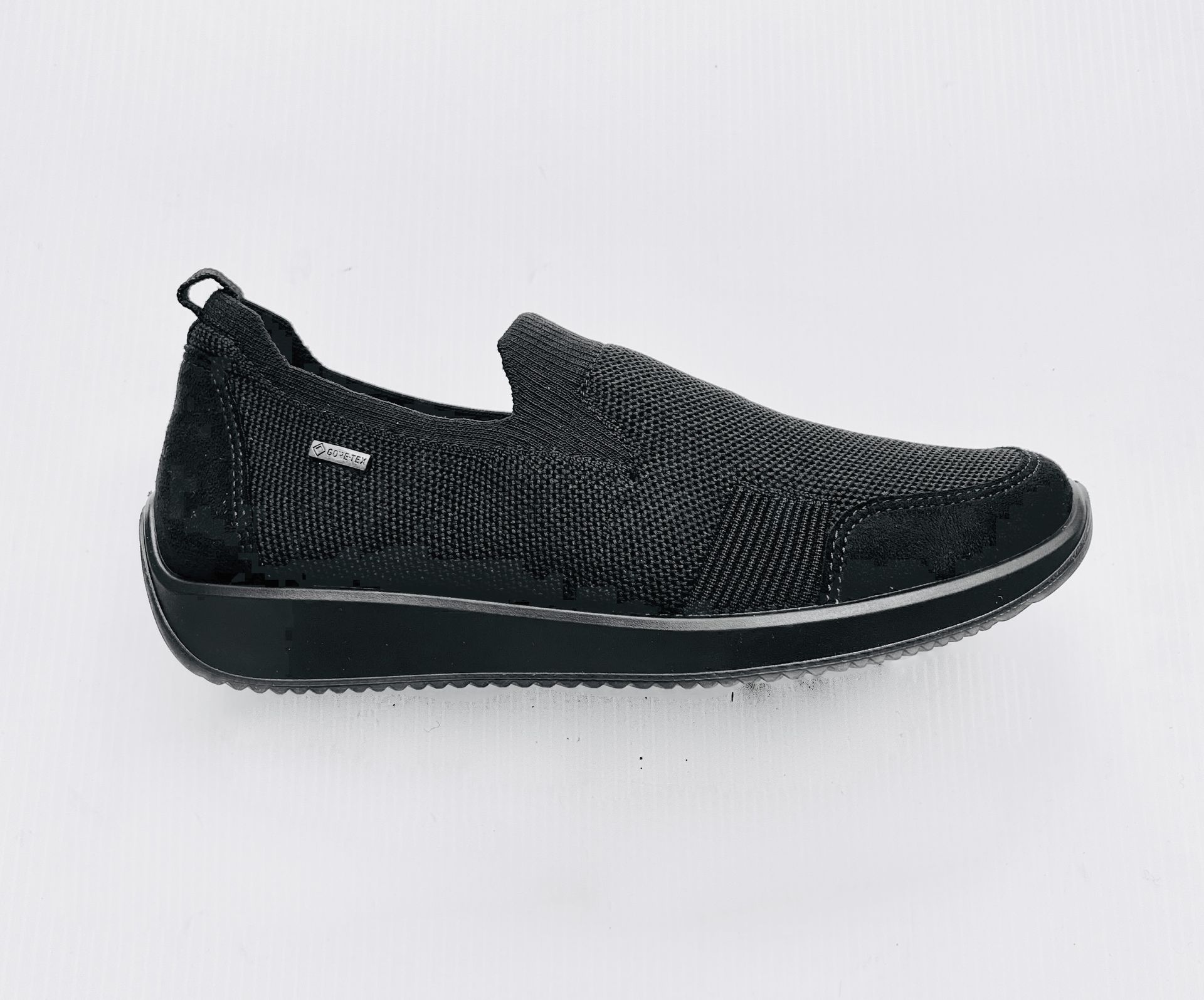 Scarpa slip-on nera con tomaia in maglia e suola nera su sfondo bianco.