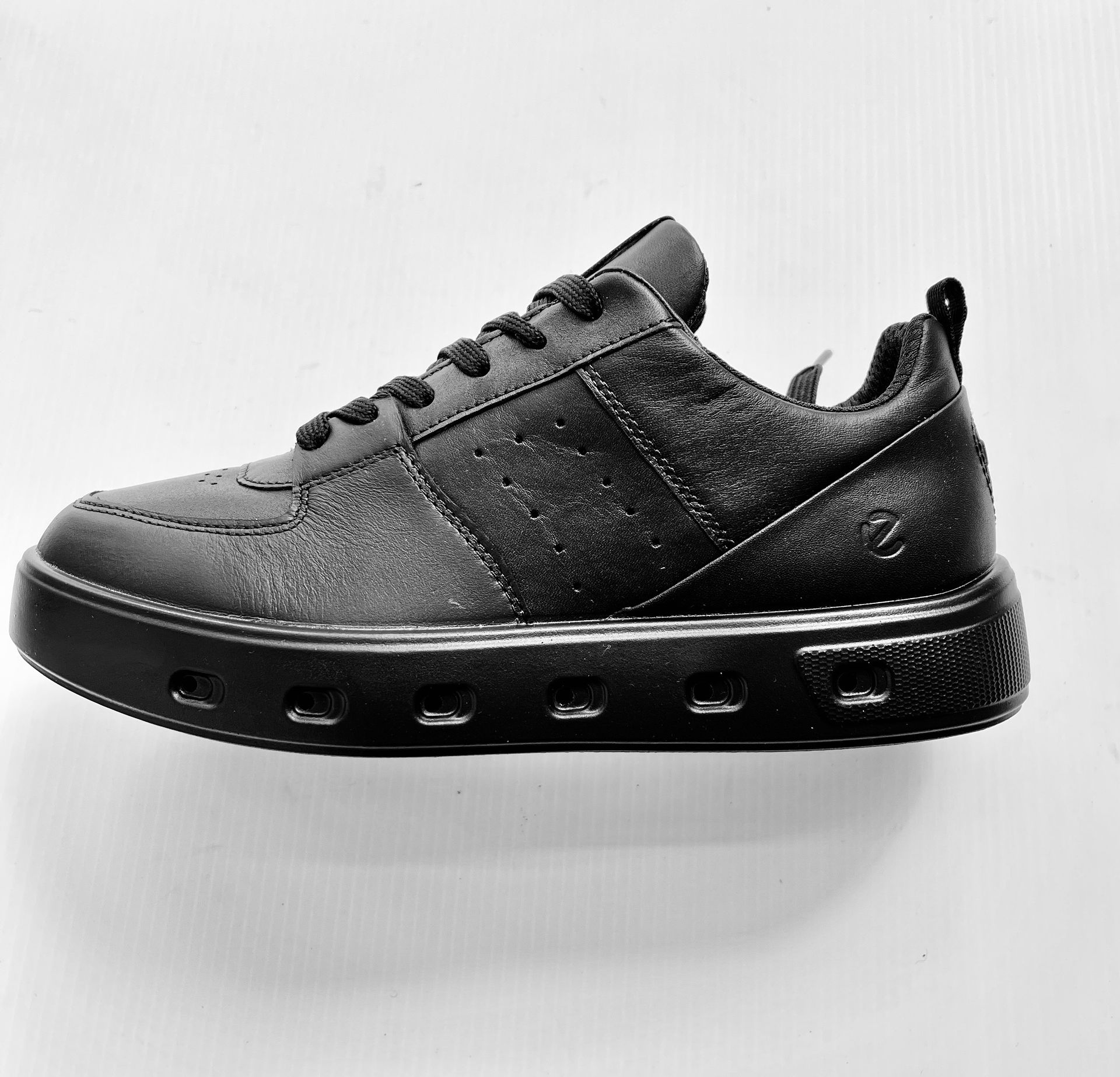 Sneaker in pelle nera con suola nera spessa.