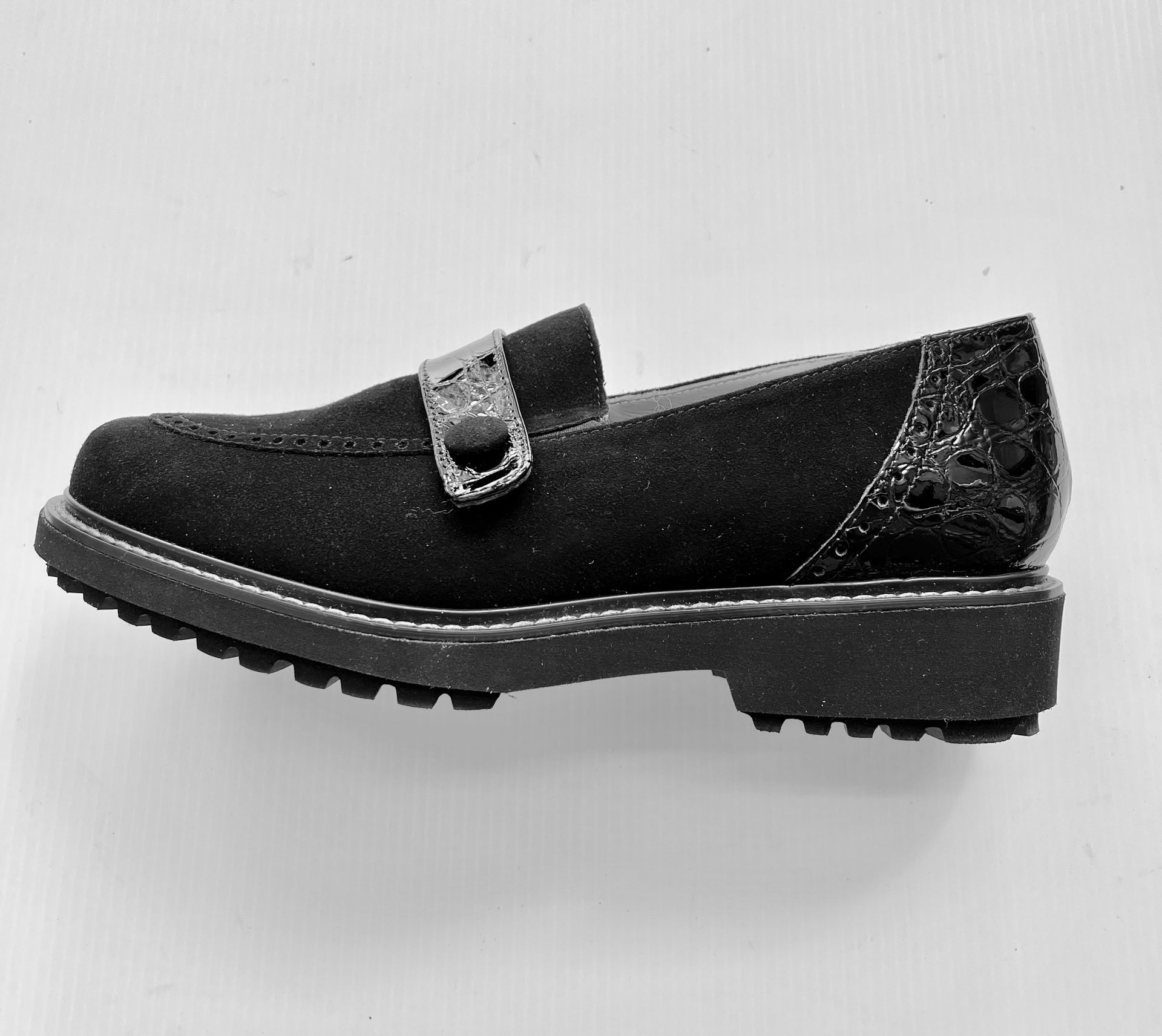 Mocassino nero con tacco testurizzato e cinturino, su suola nera con battistrada.