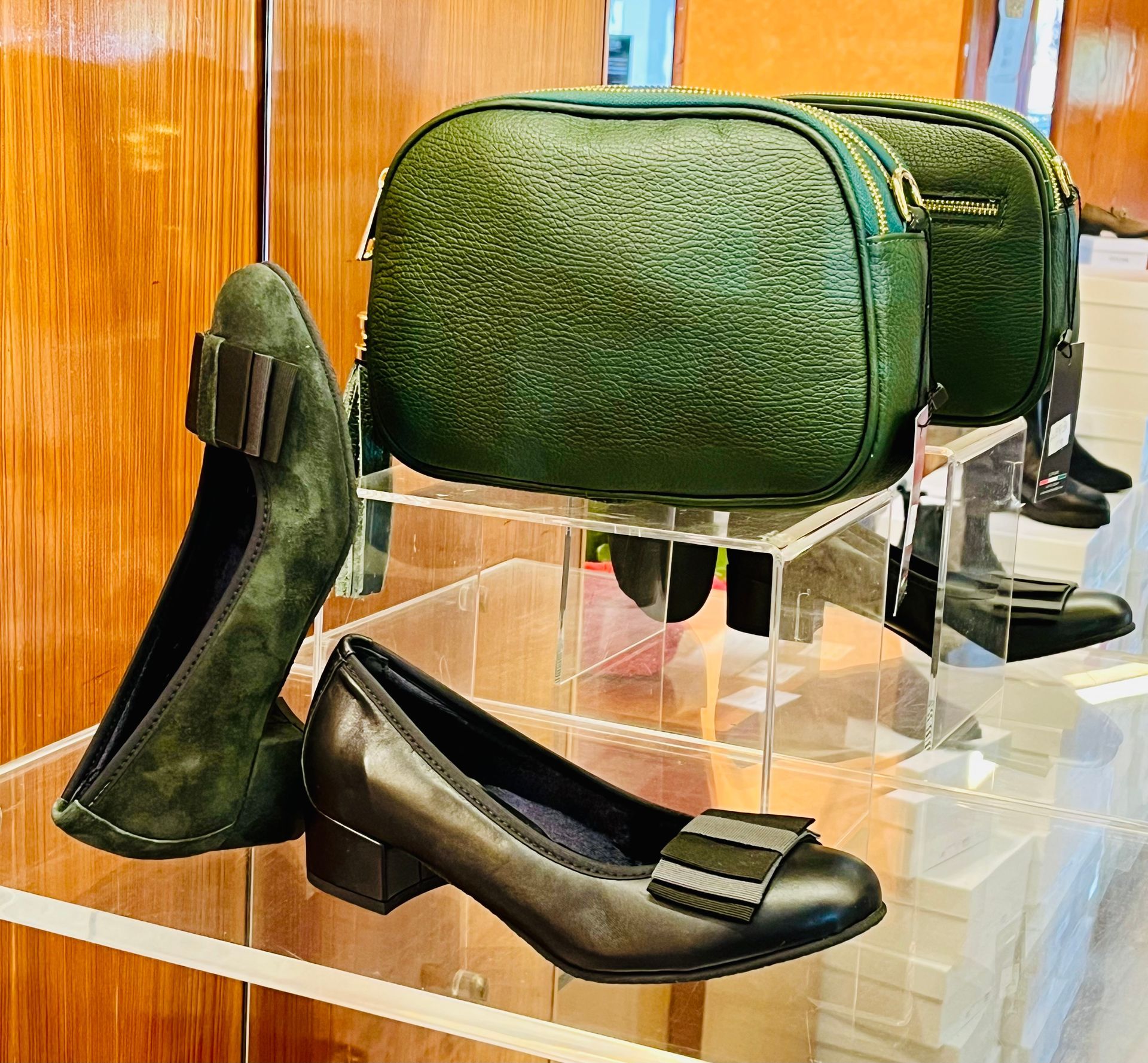 Scarpe verdi e una borsa esposte su scaffali in acrilico.