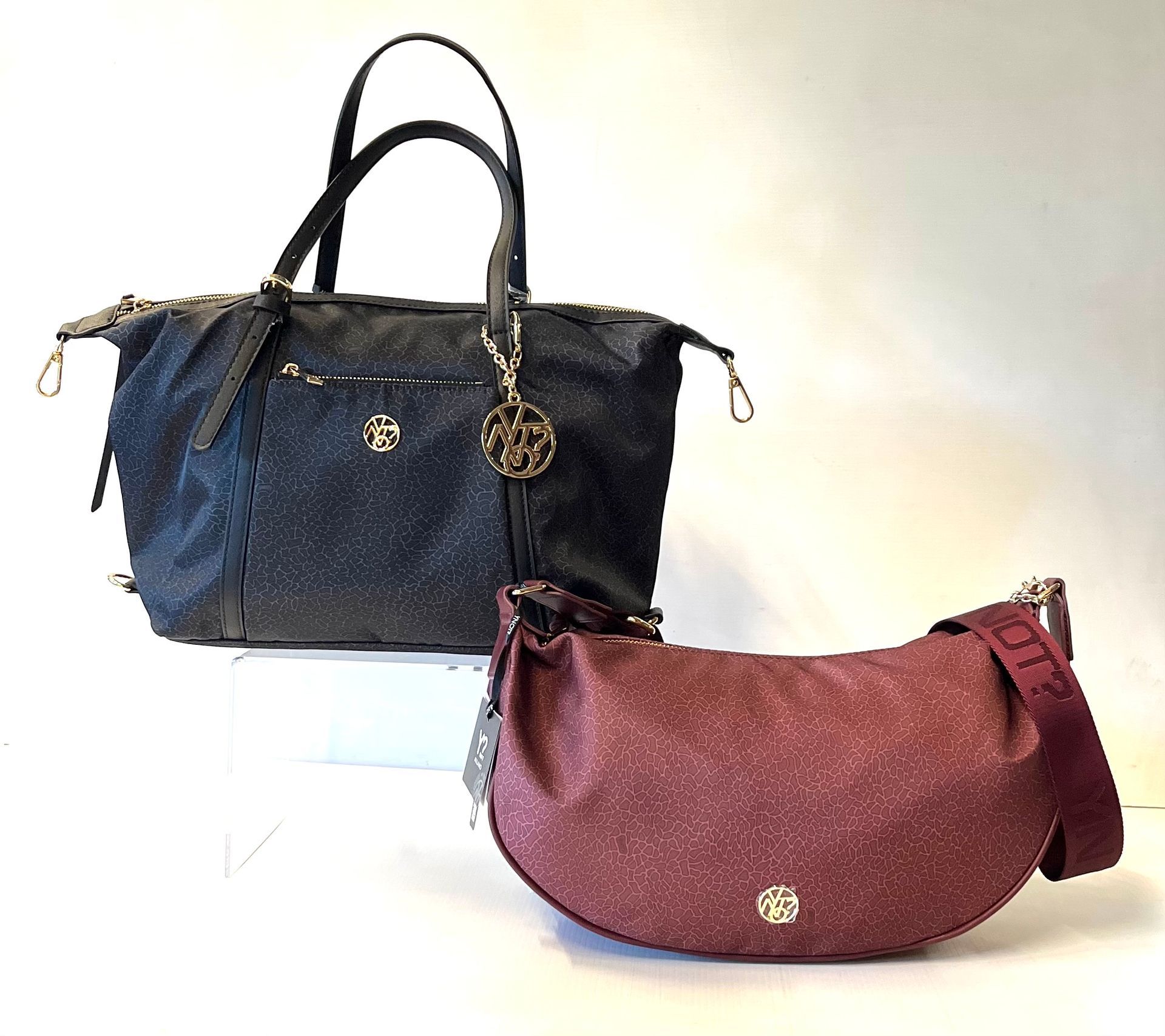 Due borse scintillanti: una tote bag nera e una borsa a mezzaluna color bordeaux.
