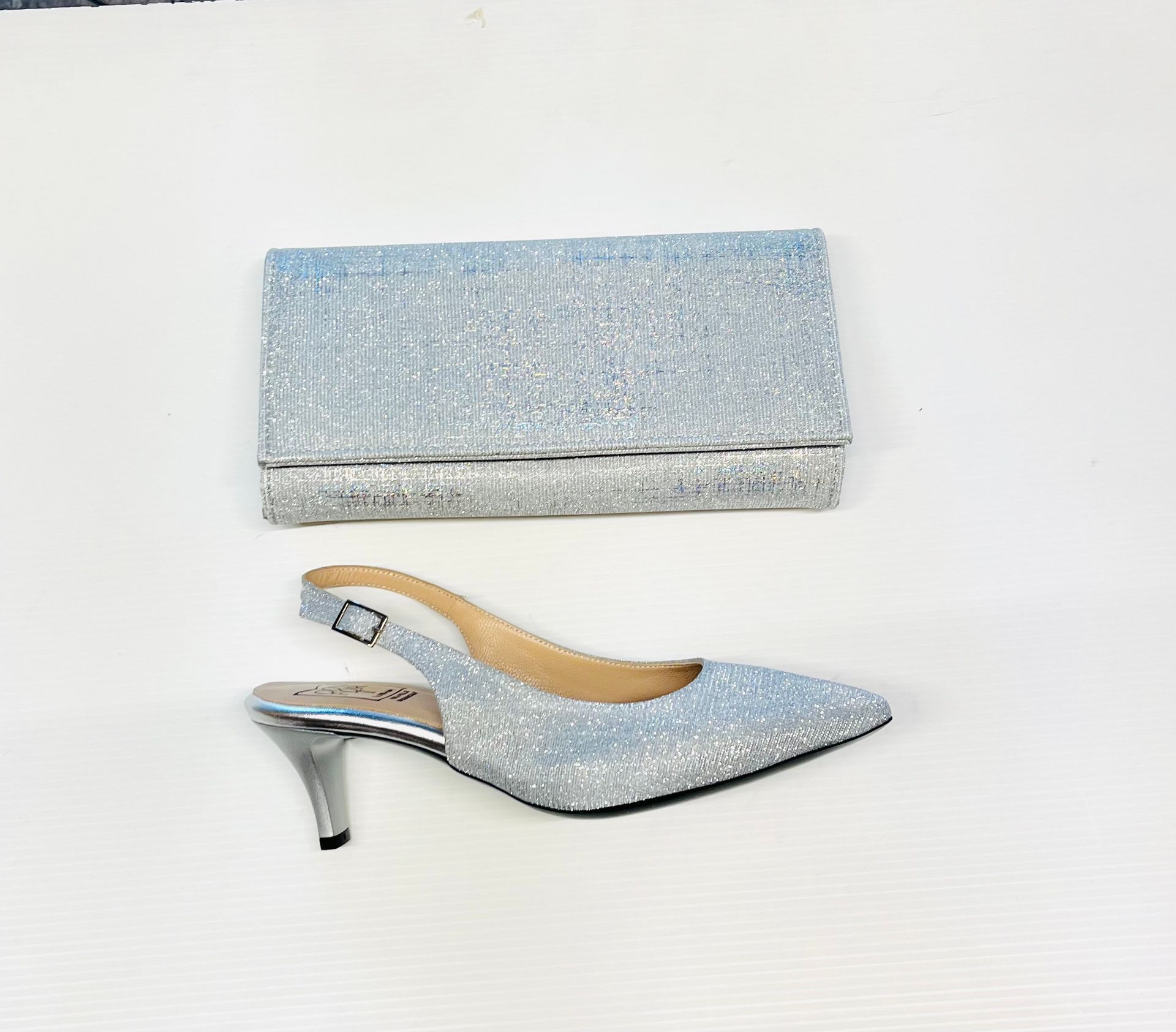 Pochette con glitter argento e tacco slingback abbinato su bianco.