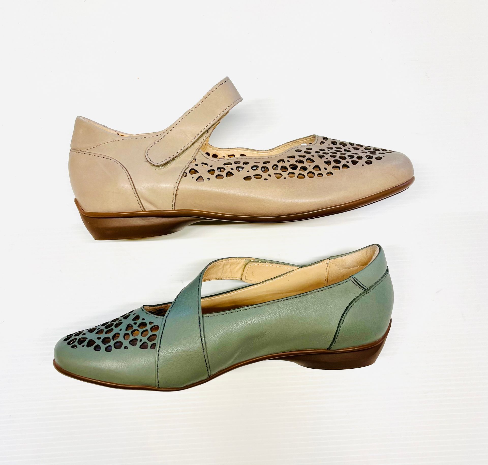 Due paia di scarpe in pelle: una Mary Jane color cuoio e una slip-on verde, entrambe con motivi traforati e tacco basso.