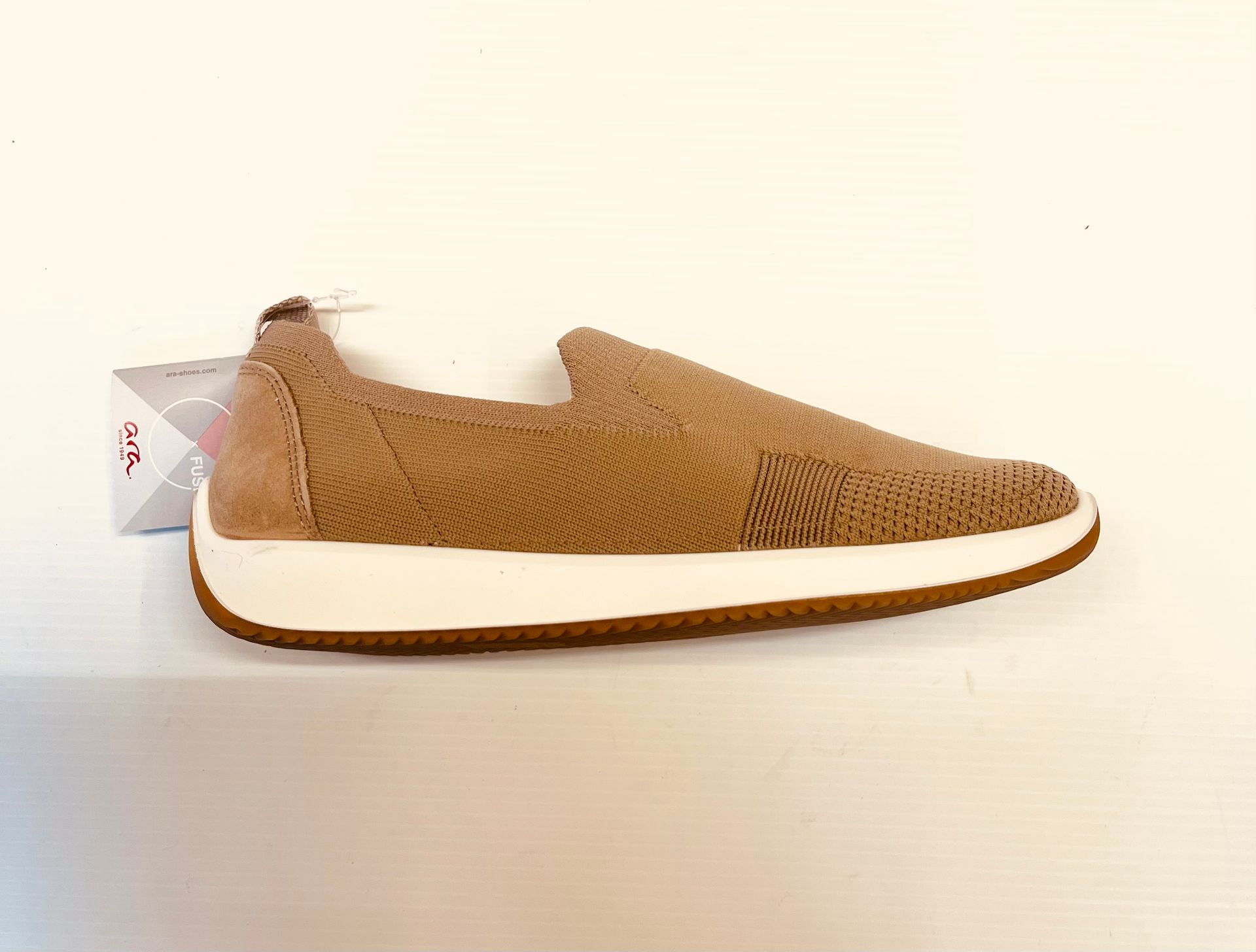 Scarpa slip-on marrone con suola bianca e rifiniture color cuoio. Etichetta allegata.