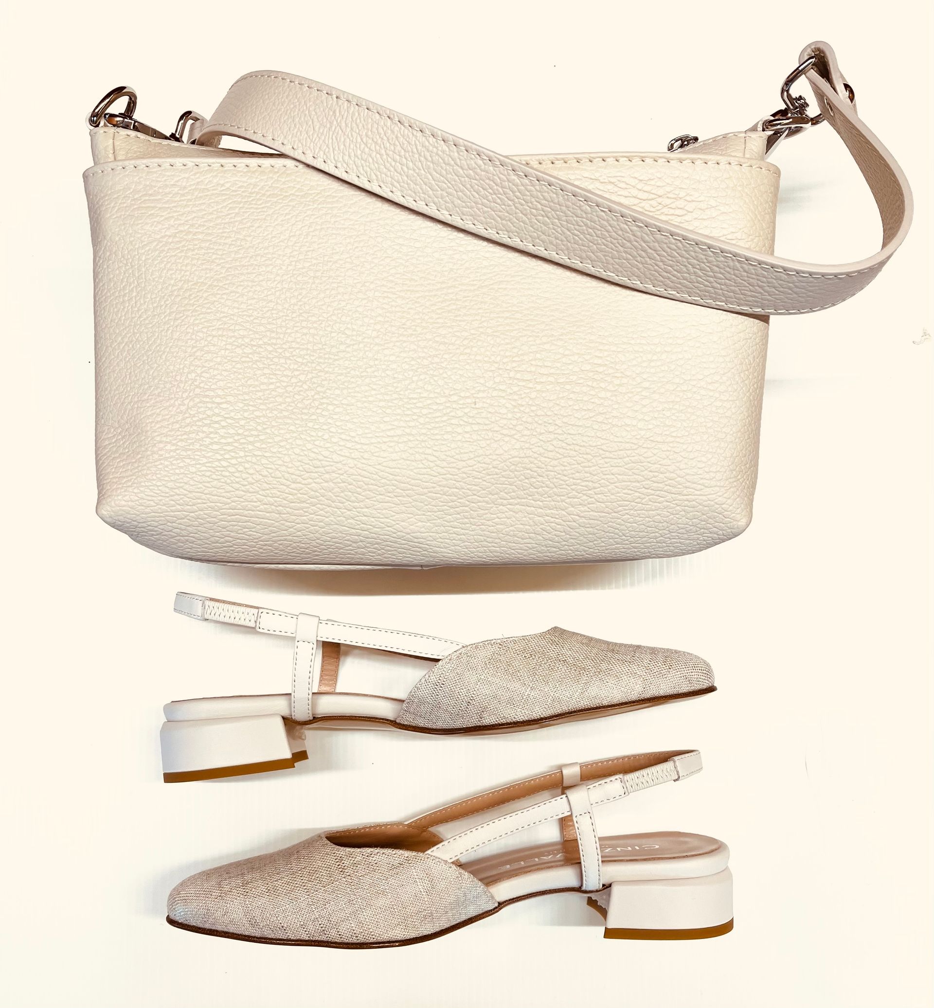 Borsa a mano color crema con tracolla, abbinata a scarpe con tacco a blocco coordinate.