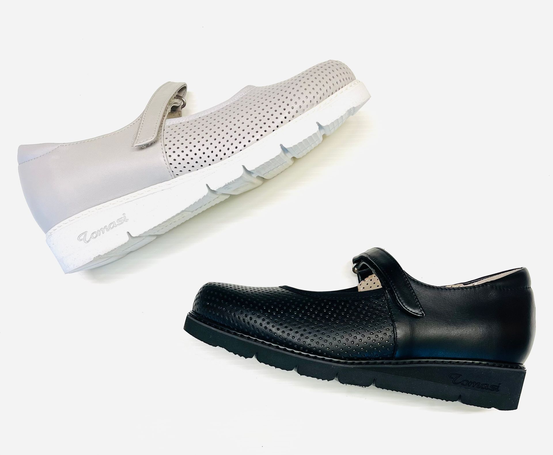 Due scarpe in stile Mary Jane, una grigia e una nera, con tomaia traforata.