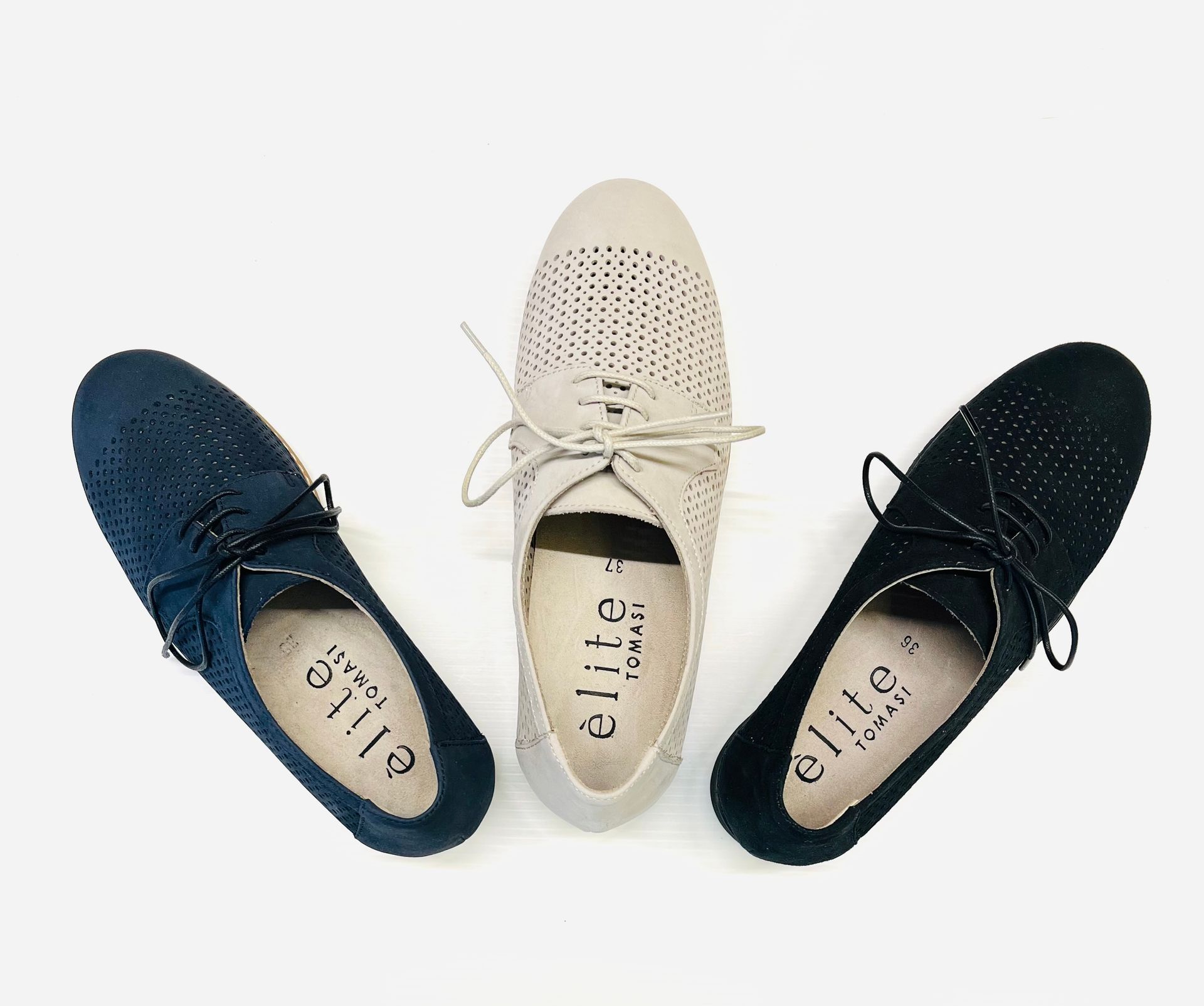 Tre paia di scarpe in pelle traforata: blu navy, beige e nere, disposte su uno sfondo bianco.