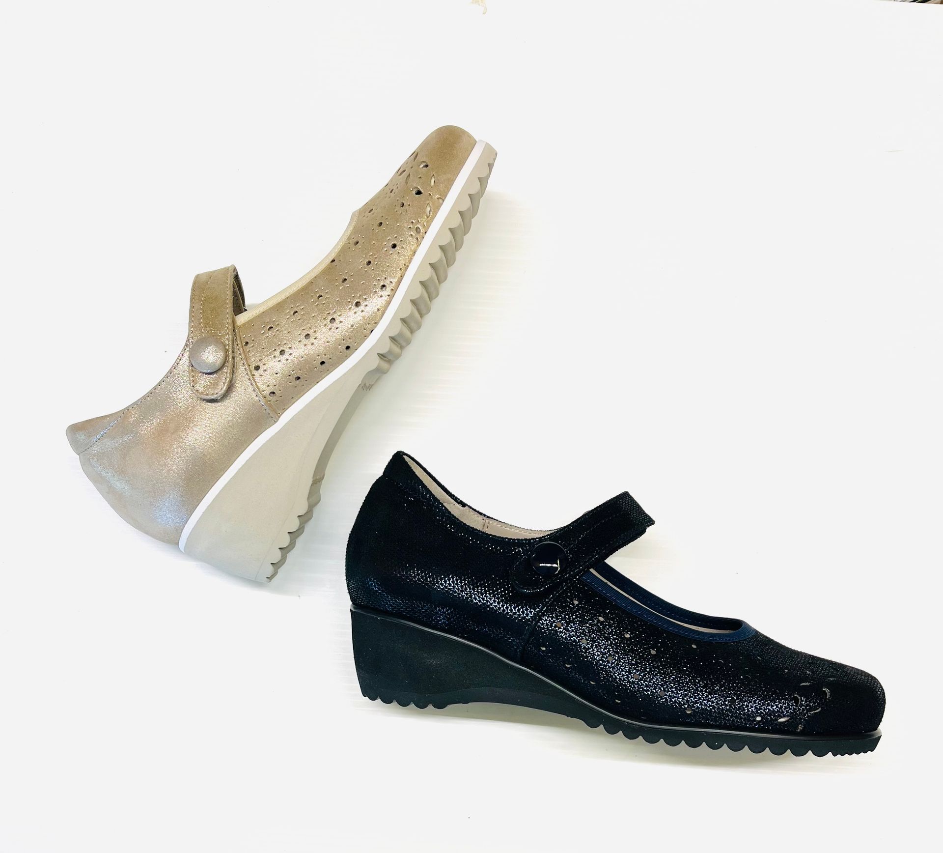 Due scarpe con zeppa in stile Mary Jane, una dorata e una nera, su sfondo bianco.