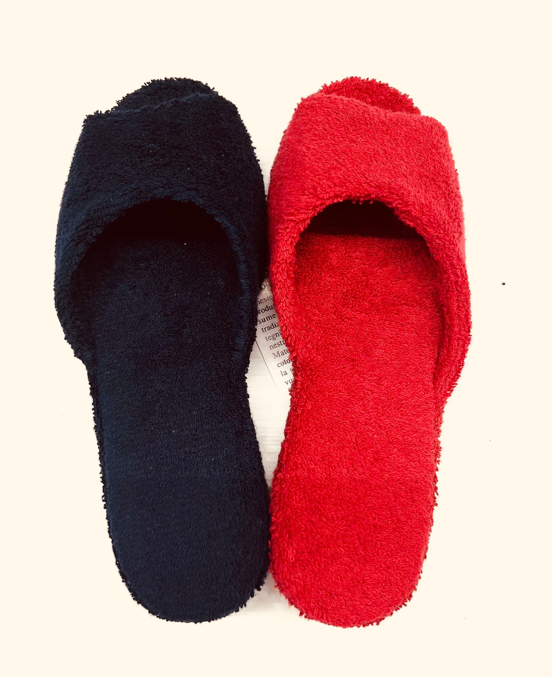 Due pantofole pelose, una blu navy e una rossa, una accanto all'altra su una superficie chiara.