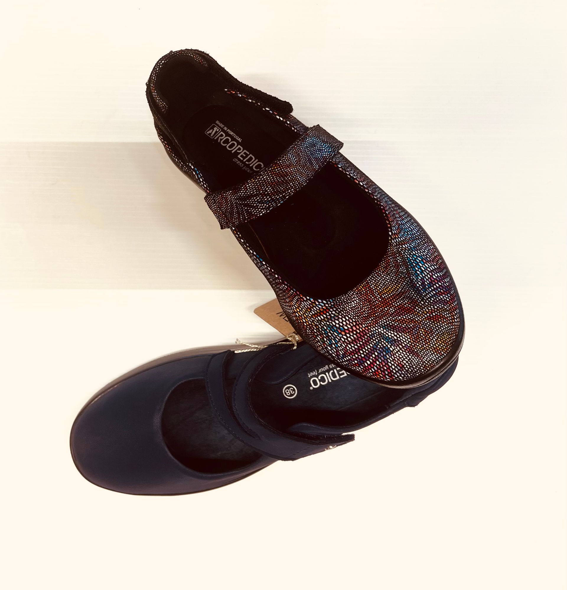 Due scarpe in stile Mary Jane, una fantasia e l'altra blu navy, su una superficie chiara.