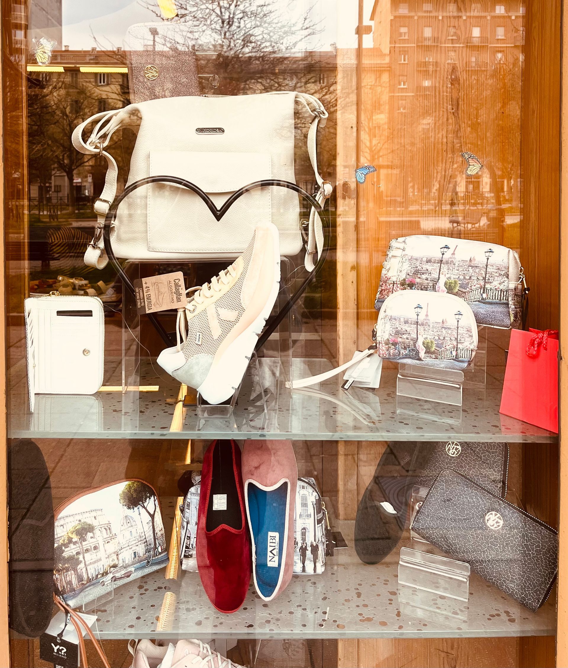 Vetrina con borse, scarpe e una borsa bianca, alcune con un motivo a cuore.