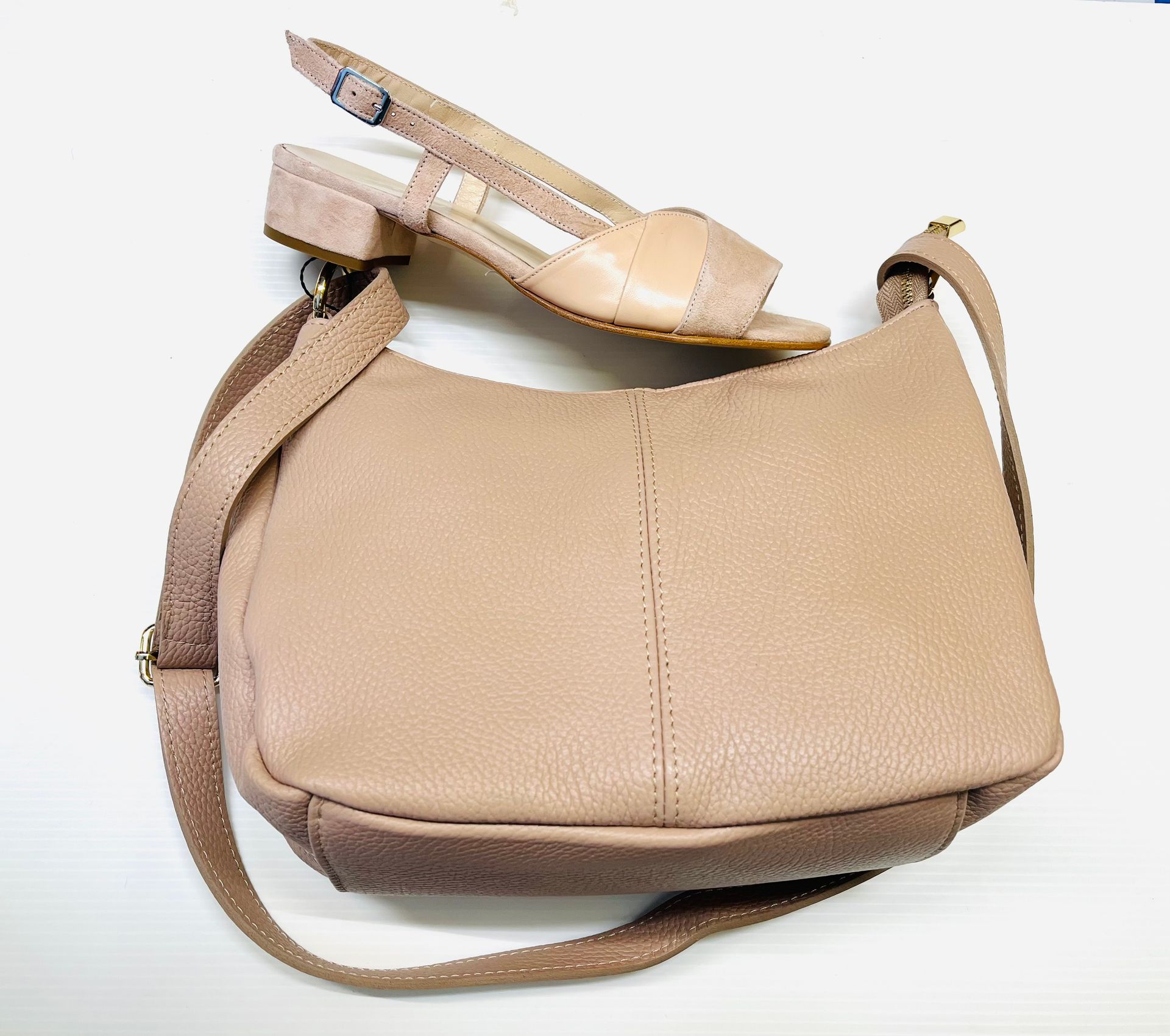 Borsa a mano in pelle marrone chiaro con sandalo abbinato su superficie bianca.