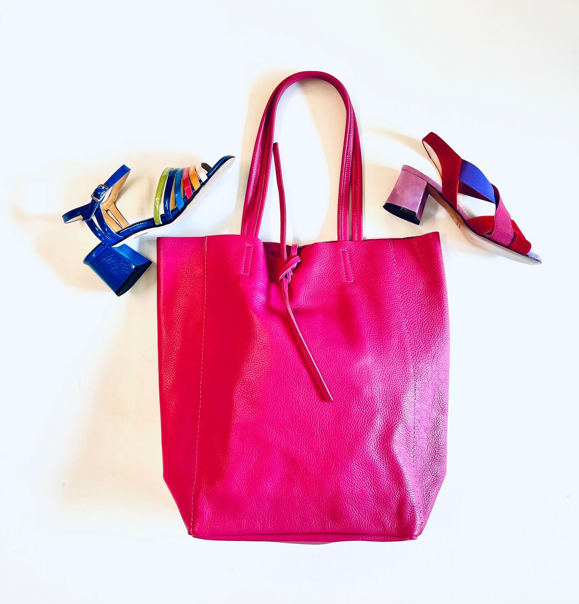 Borsa tote rosa con due tacchi colorati su sfondo bianco.