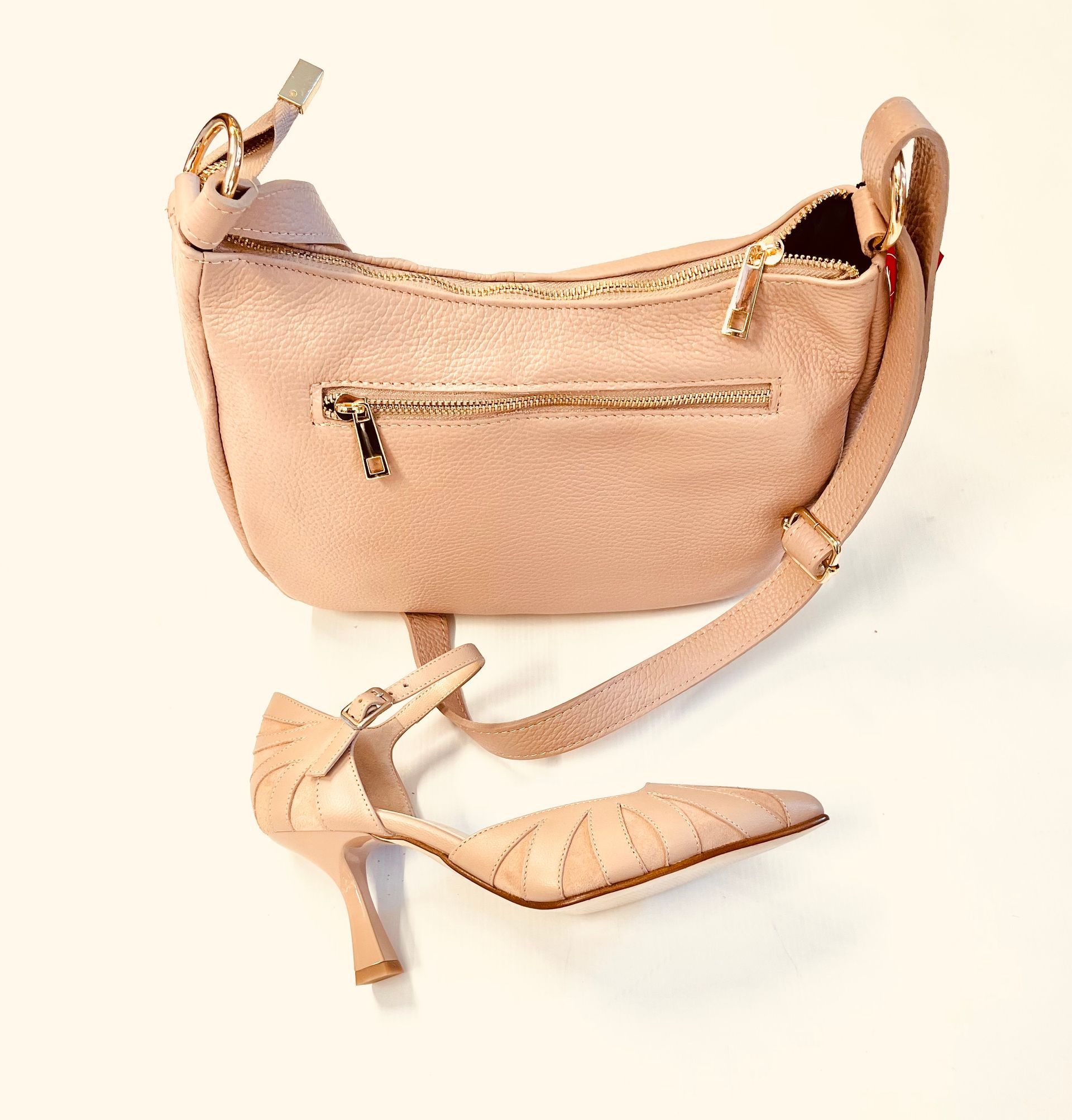 Borsa in pelle rosa e scarpa con tacco alto su sfondo bianco.