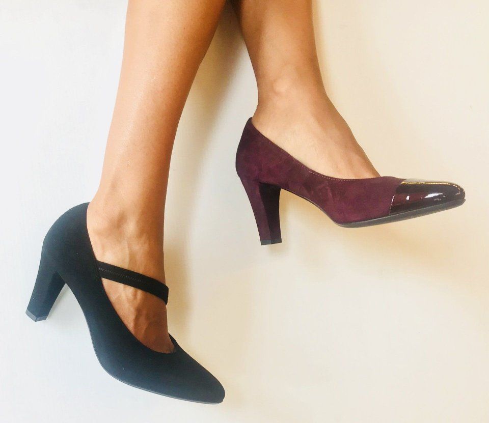 Due piedi che indossano scarpe con tacchi di colori diversi. Una nera, l'altra bordeaux.