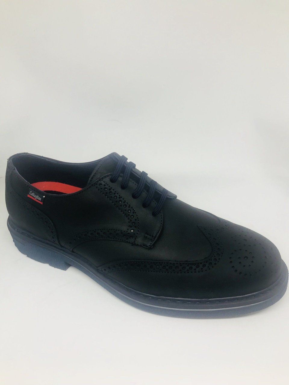 Scarpa brogue nera con suola blu su sfondo bianco.