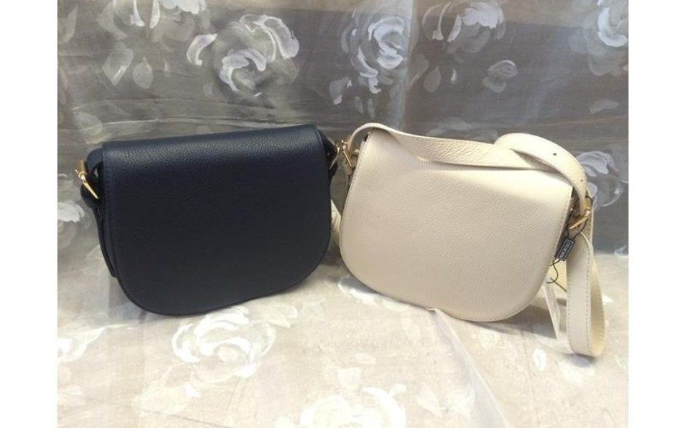 Due borse laterali in pelle: una blu navy, una color crema, su uno sfondo floreale.