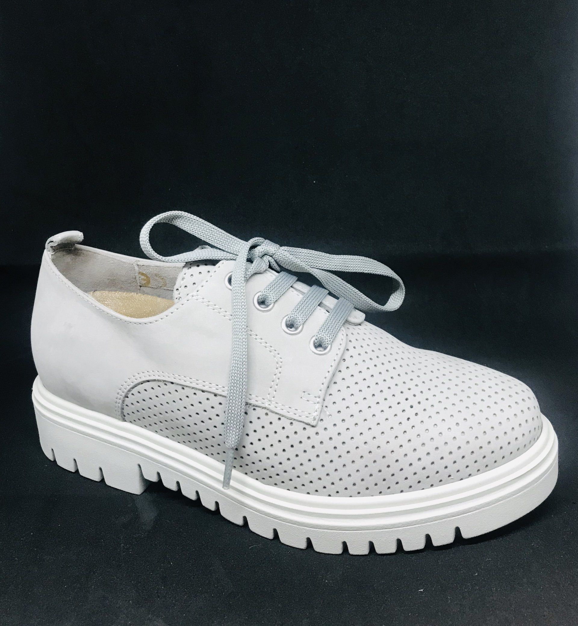 Scarpa in pelle traforata grigio chiaro con suola e lacci bianchi.