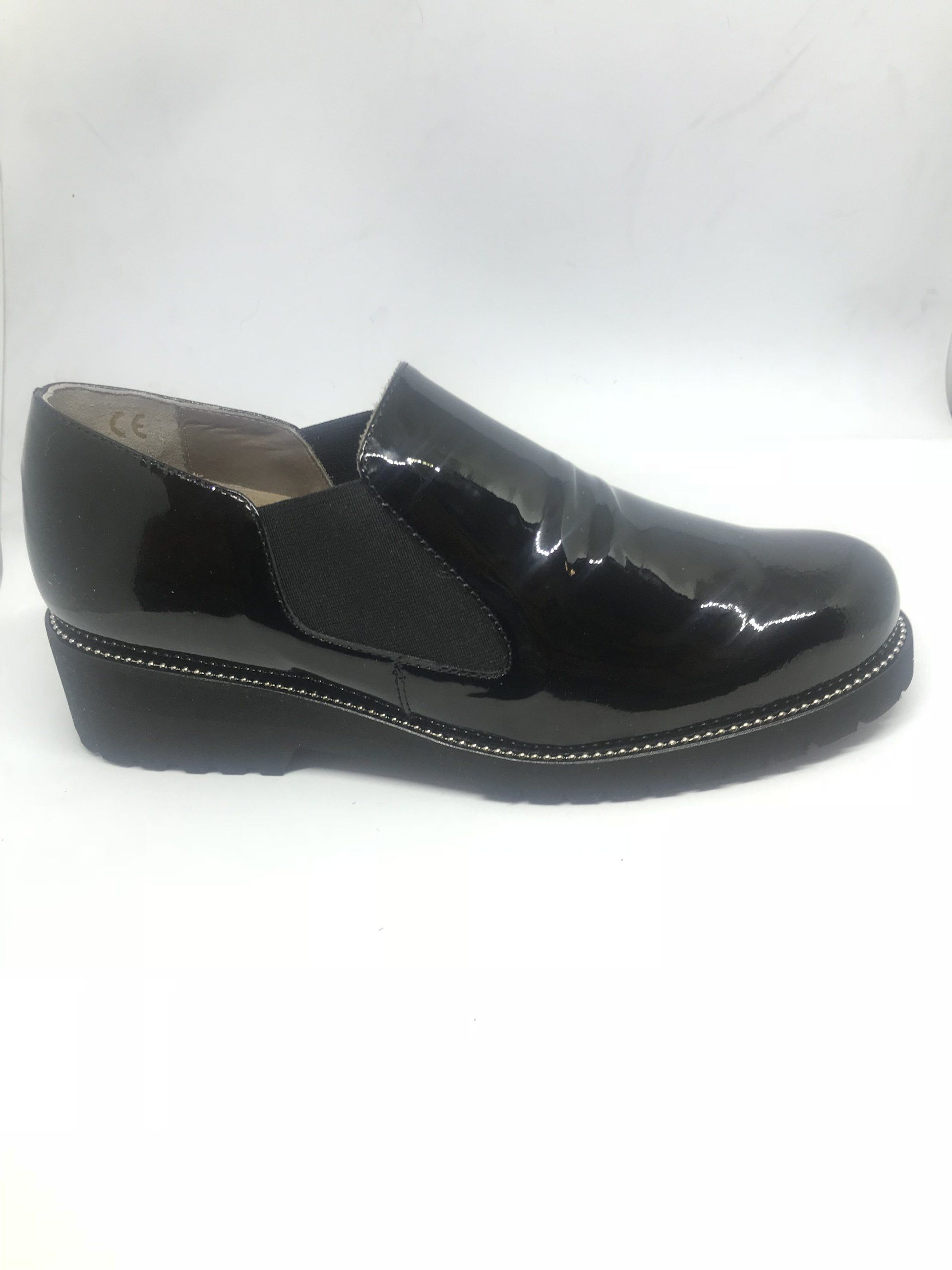 Scarpa slip-on in vernice nera con elastico laterale e tacco a zeppa.
