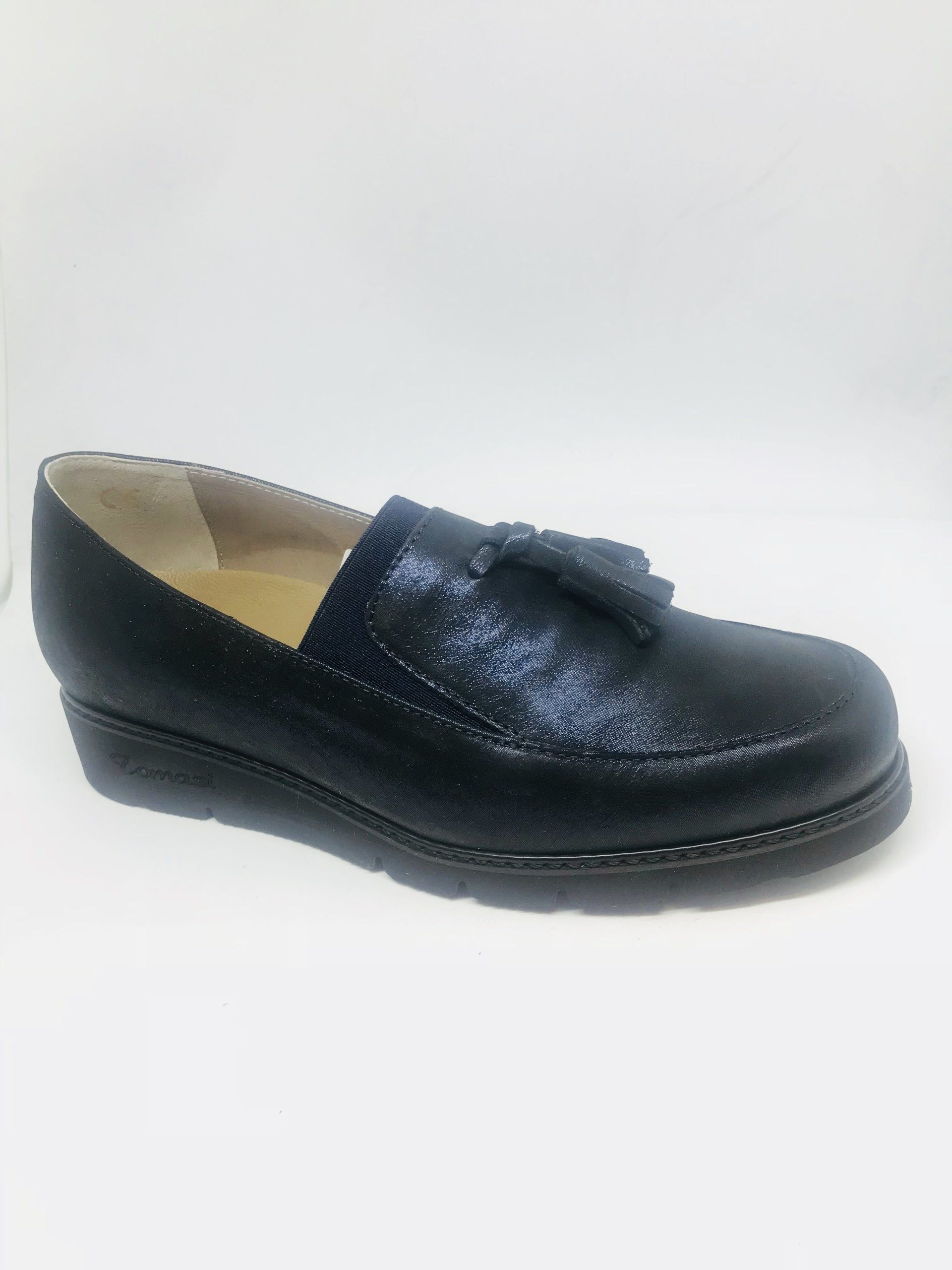 Mocassino nero testurizzato con nappa, su sfondo bianco.