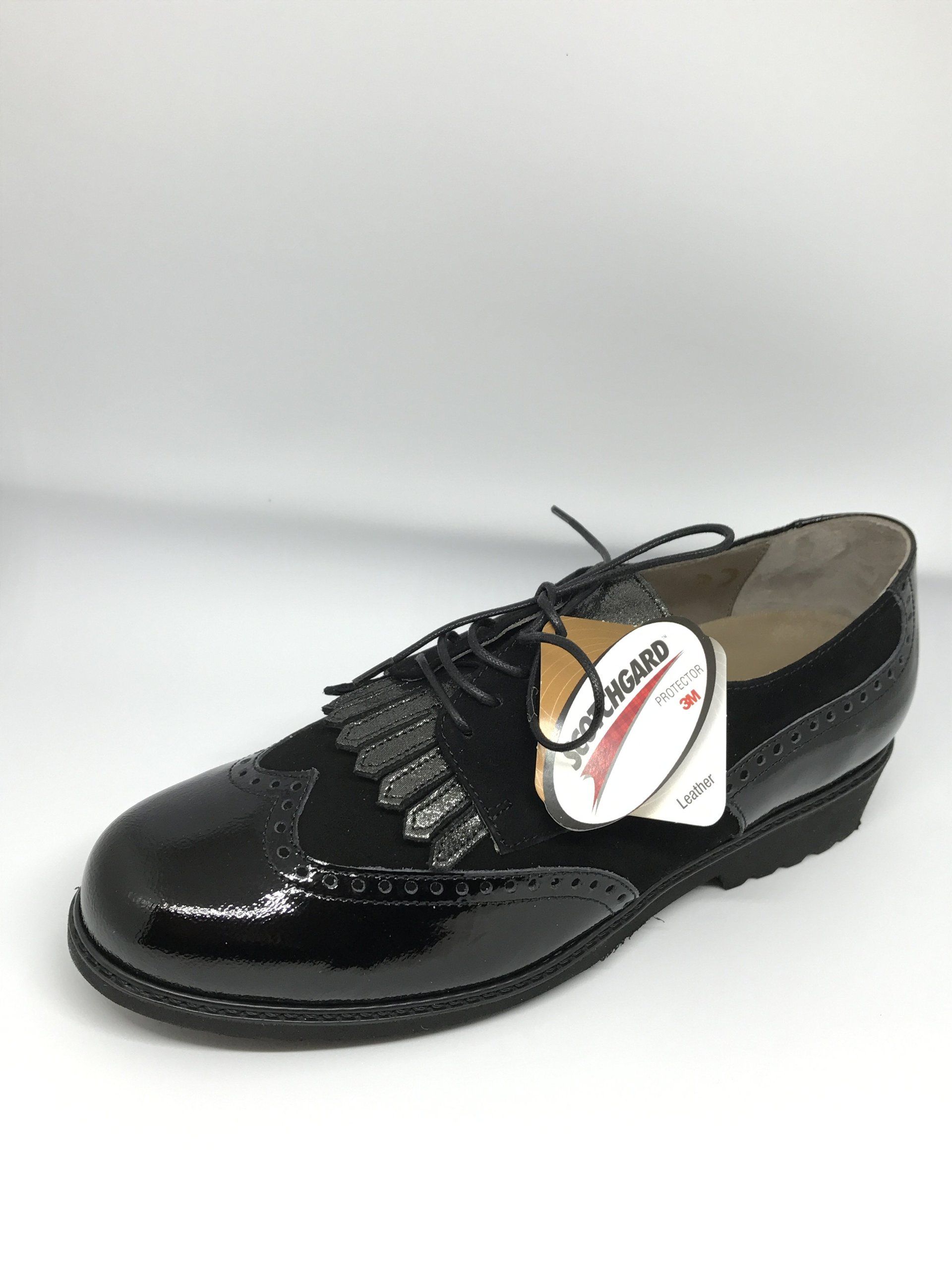 Scarpa in vernice nera con punta a coda di rondine e targhetta attaccata.