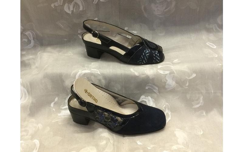 Due scarpe blu navy con cinturino posteriore e tacco basso, appoggiate su una superficie.