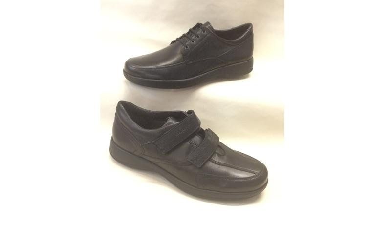 Due scarpe nere: una con i lacci, l'altra con il velcro. Entrambe su una superficie bianca.