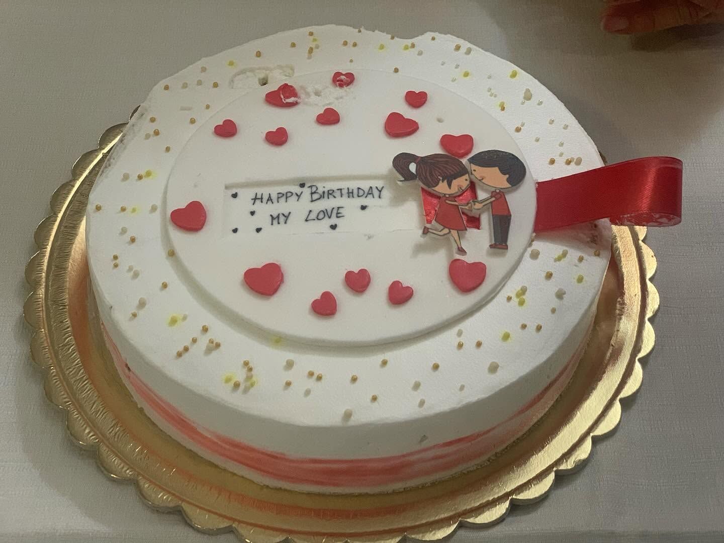 Torta di compleanno con glassa bianca, cuori rossi e nastro rosso