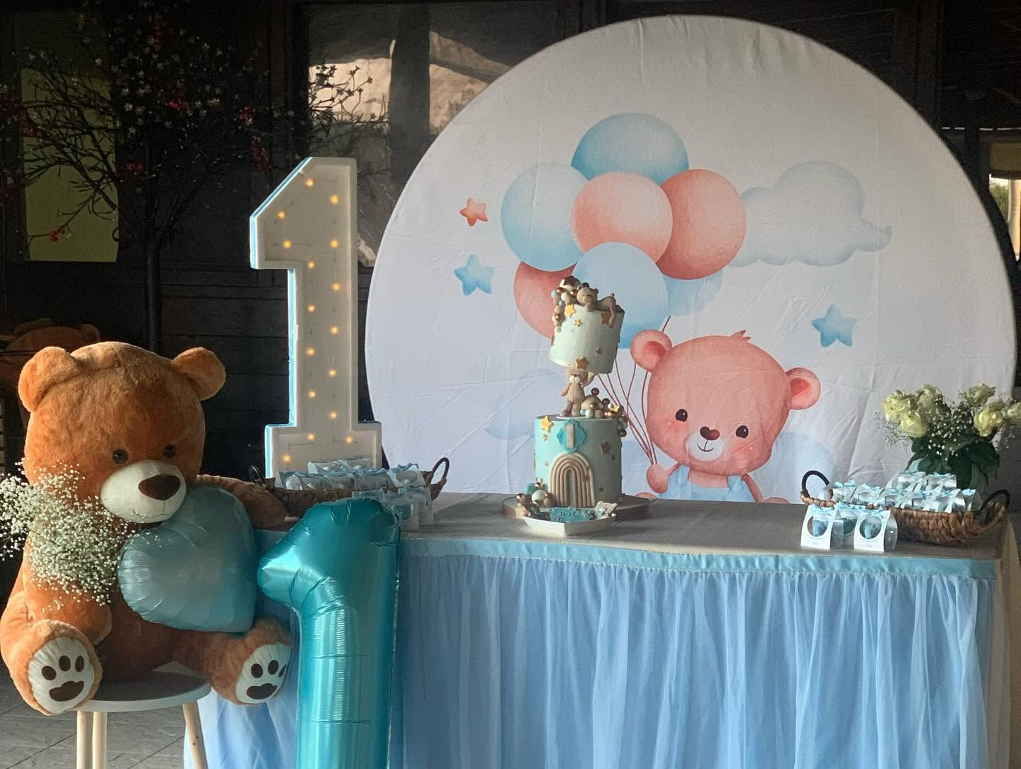 Tavolo dei dolci per il primo compleanno a tema orsacchiotto, con palloncini, un grande numero