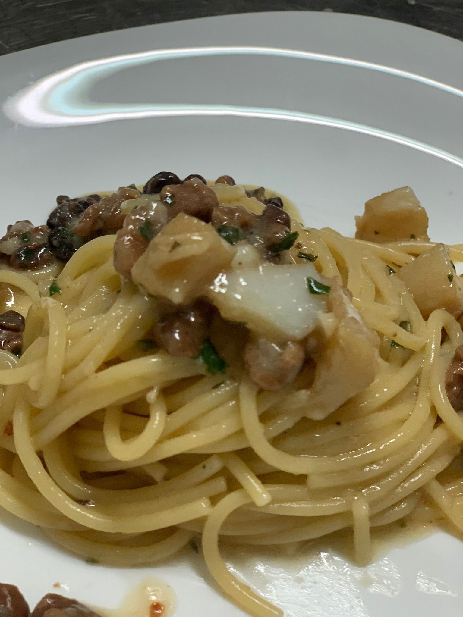Piatto di spaghetti con vongole ed erbe aromatiche su un piatto bianco