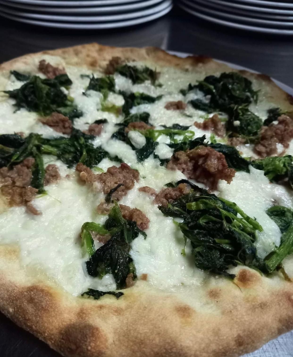 Una pizza con spinaci e funghi e formaggio